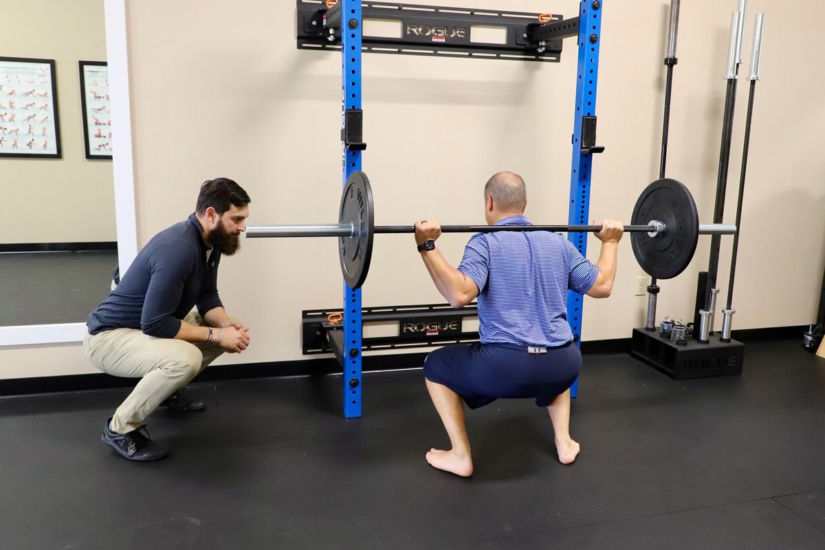 chiropractor monitoring patient's weightlifting form